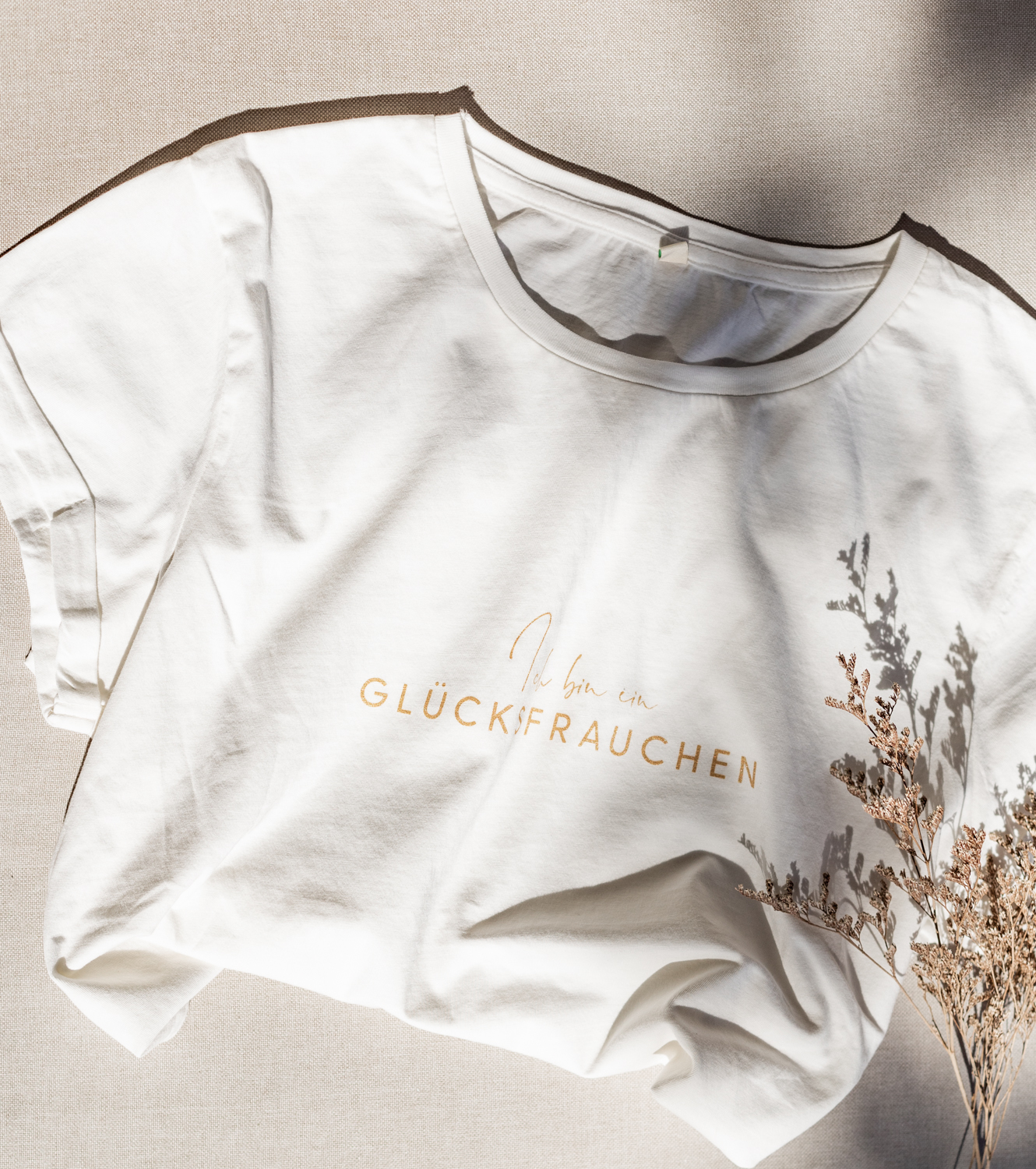 Weisses T-Shirt mit Trockenblumen verziert und Schriftzug Glücksfrauchen