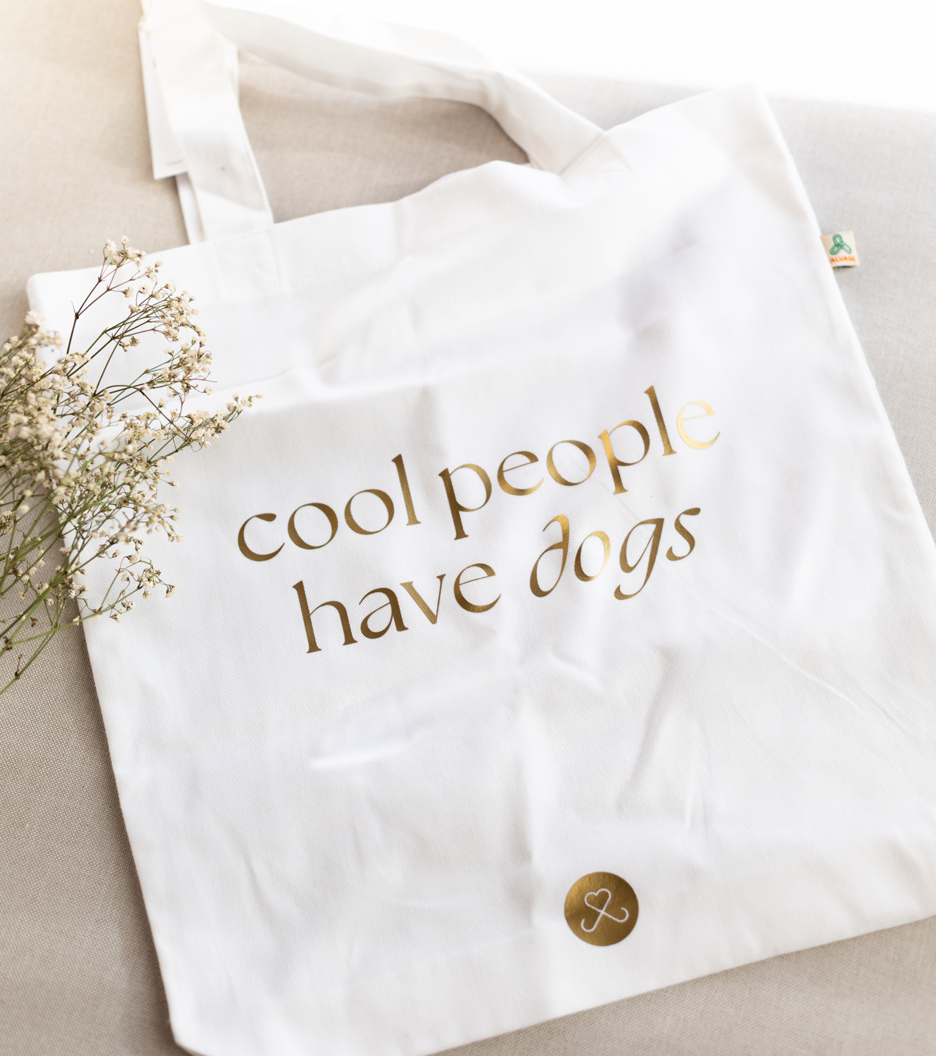 Ansicht von weisser Tasche mit goldene Schriftzug cool people have dogs
